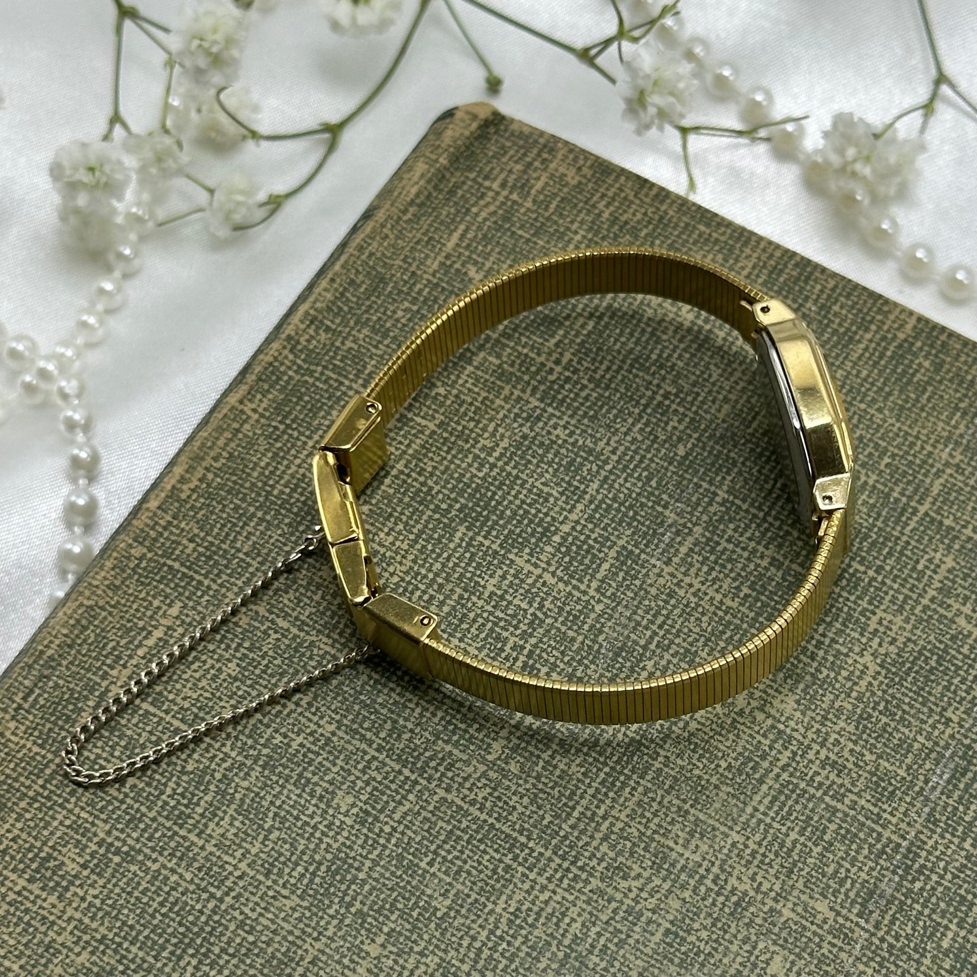 square dial Seiko watch with quartz movement and clasp band.